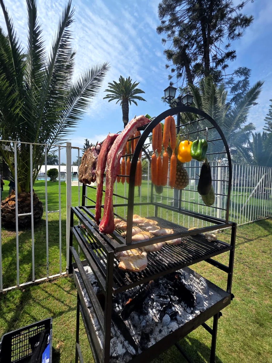 Asador con cortes, verduras y frutas colgando